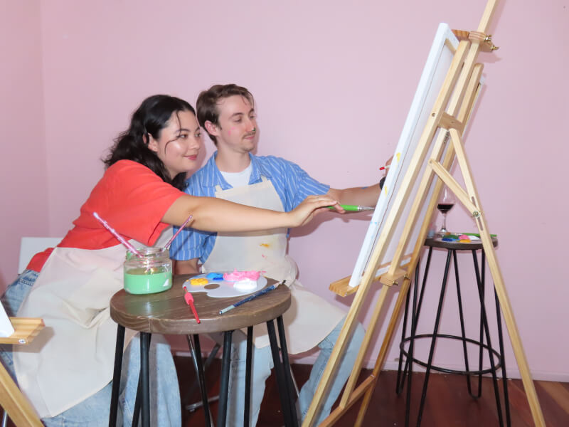 Man and woman painting on a canvas in a painting class