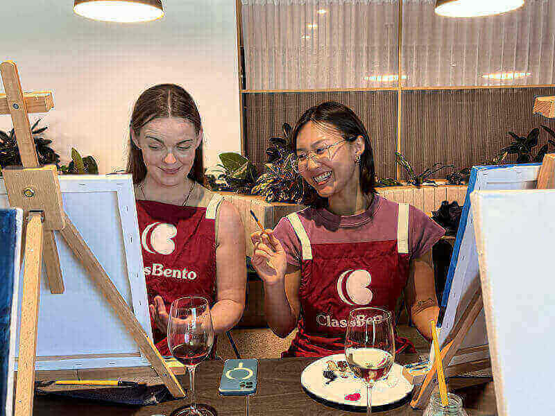 Two women smiling in a painting class