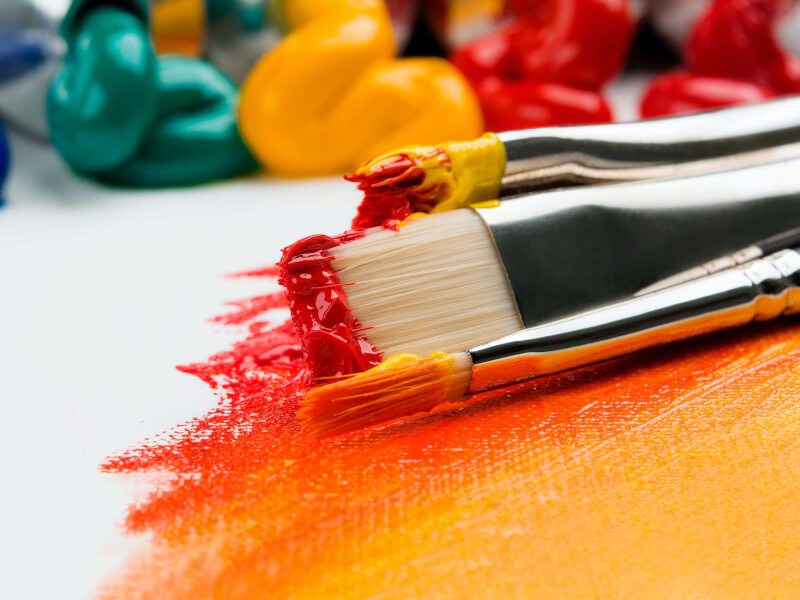 Paint brushes with paint on the bristles placed on a canvas