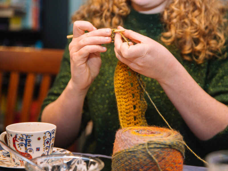 A woman's hands crocheting using colourful wool.