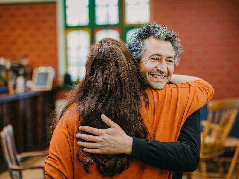 Man smiling while hugging a woman.