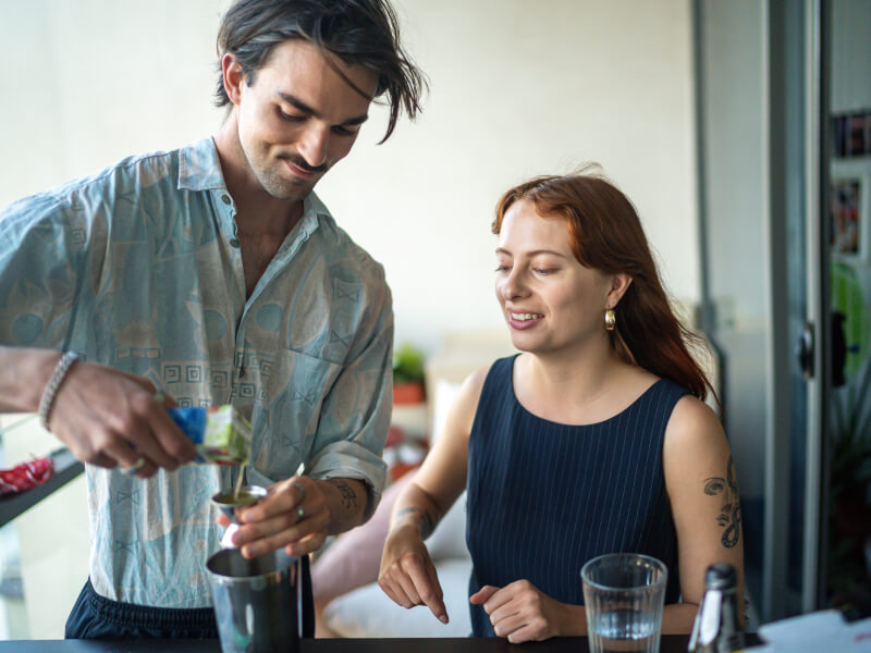 A man and woman are pouring juice into a shot measure to make DIY cocktails
