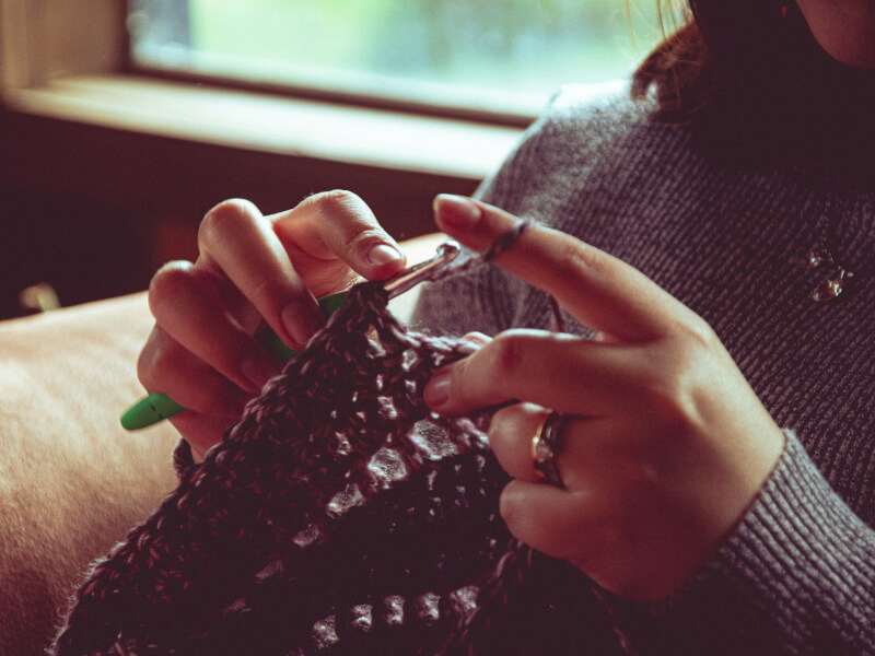 Close up of a person knitting with grey yarn