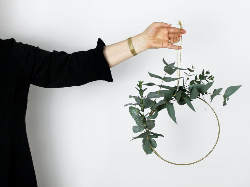 A person holds up a half finished homemade christmas wreath