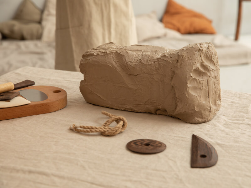Slab of clay surrounded by DIY pottery tools. 