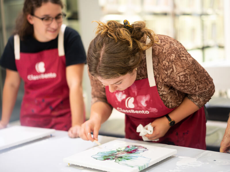 Women wearing aprons making fluid art at a hen party.