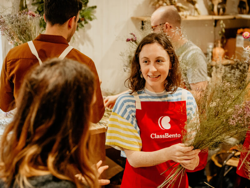 A florist is teaching a woman how to make a dried flower bouquet