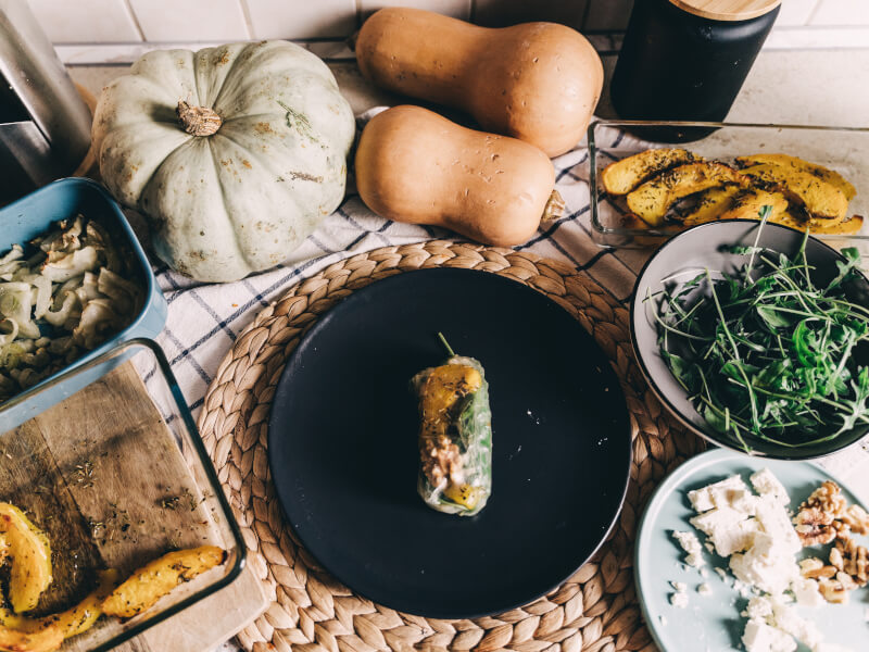 A summer roll on a plate surrounded by vegetables.