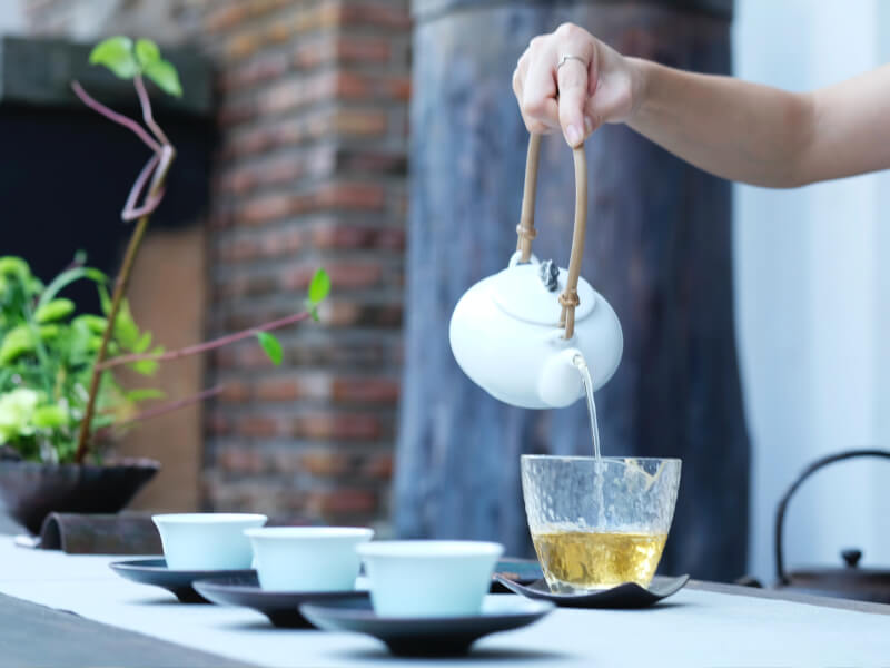 Tea being poured from a white tea pot during a tea tasting class.