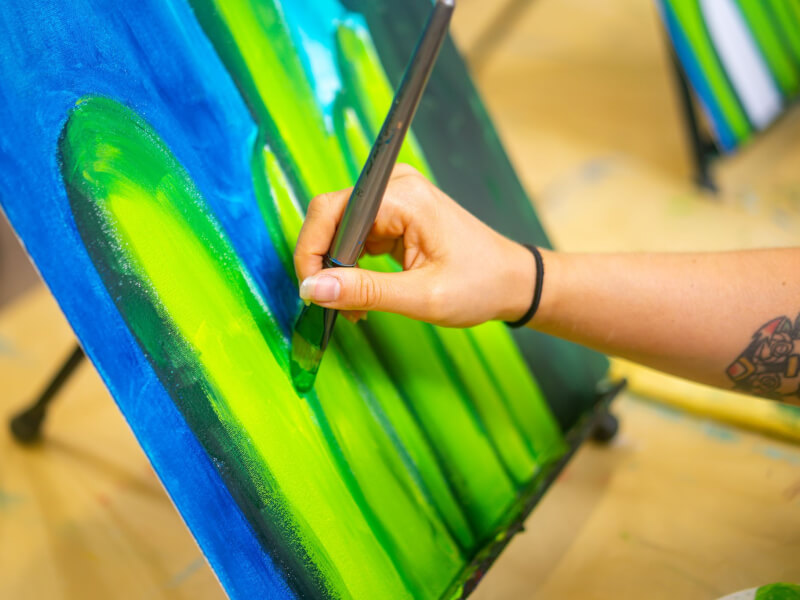Person painting a cactus during an art class.