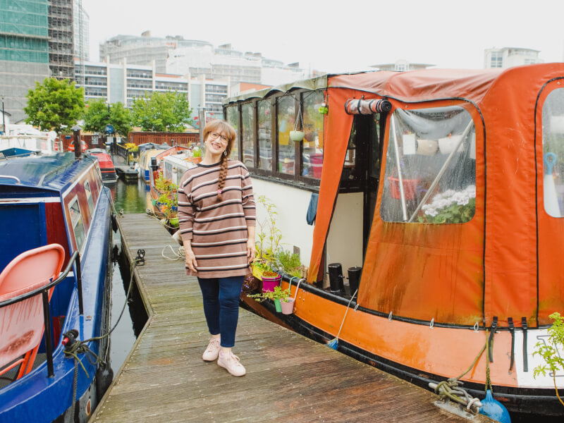 Tere from Tere and Colin Experiences standing in front of their red and blue houseboat