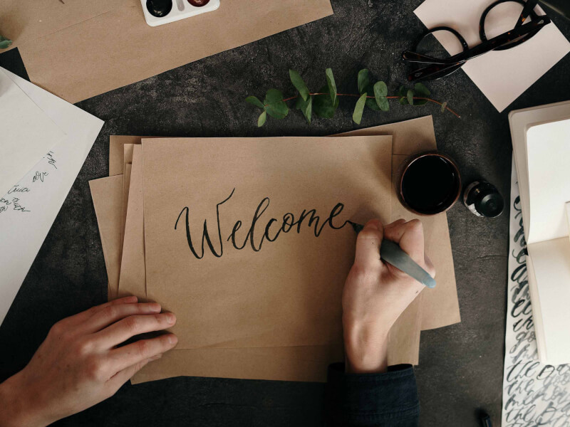A person writing on a piece of paper using calligraphy