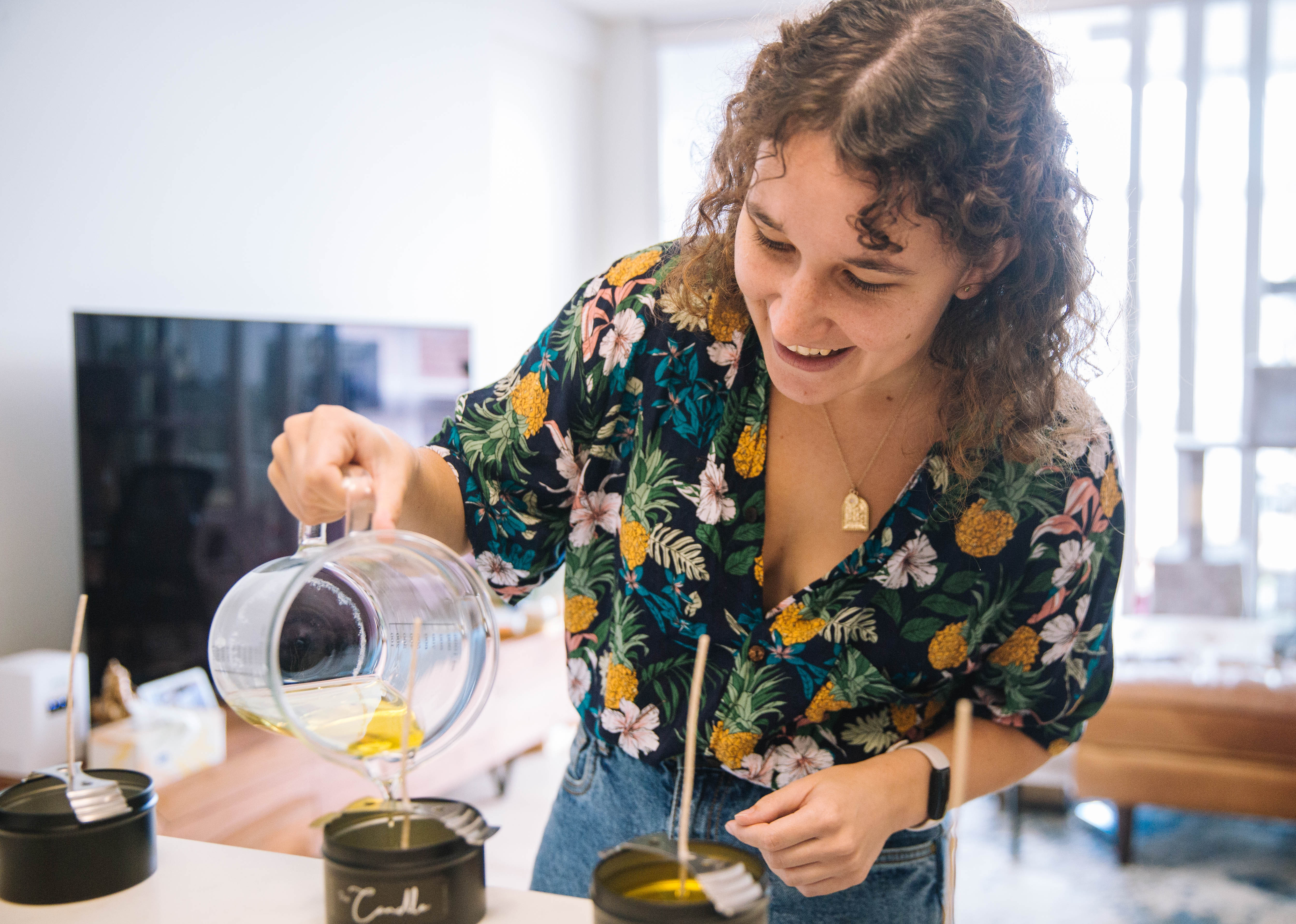 A woman is pouring melted wax into a container at a candle making class