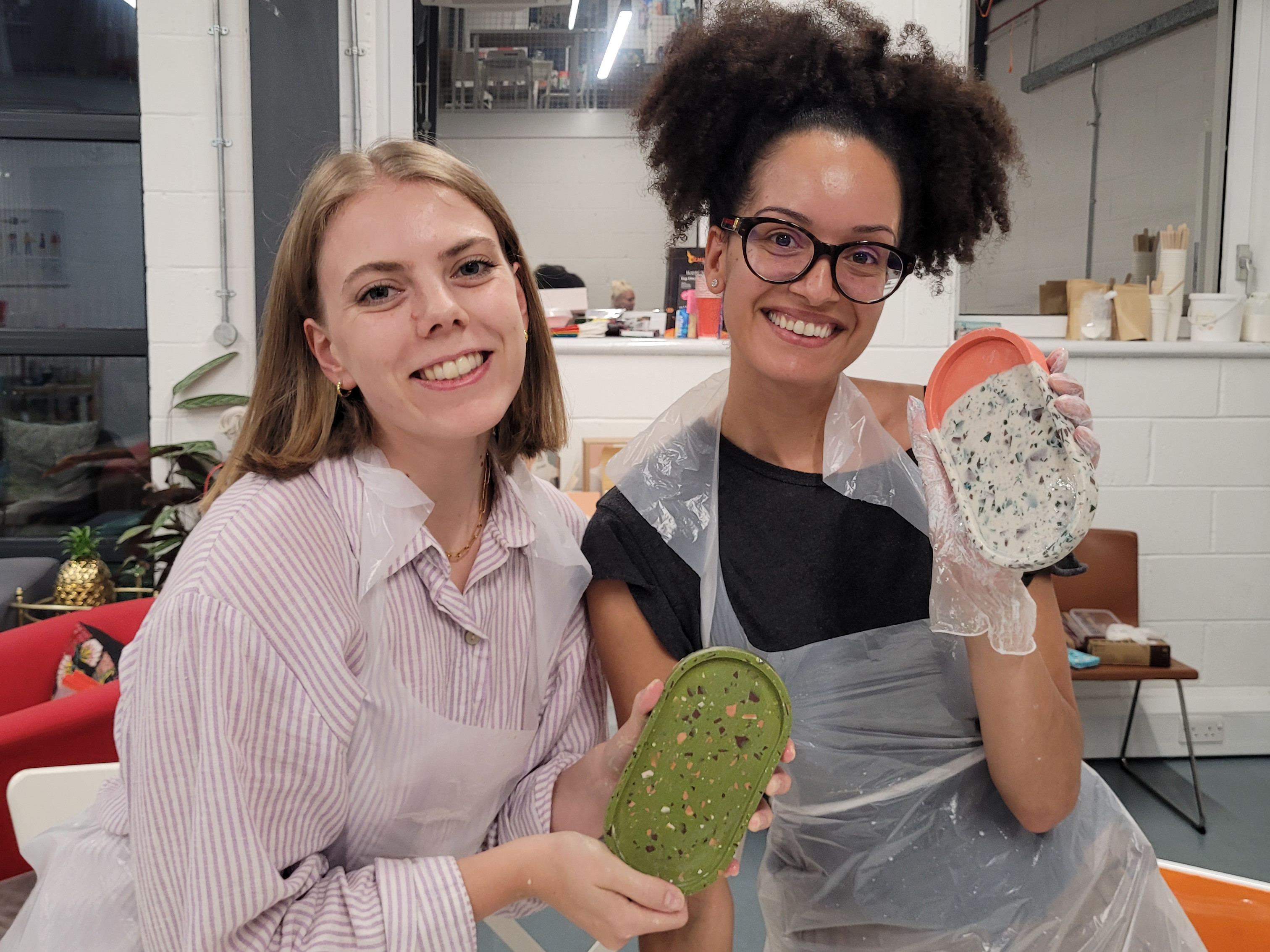 Two women showing off the resin coasters they've made