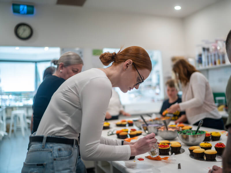 A group of people are decorating cupcakes at a baking class in Edinburgh
