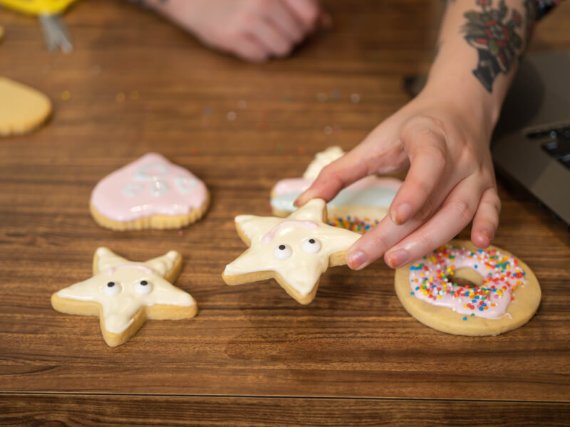 A person holding a star shaped biscuit decorated with a smiling face using icing