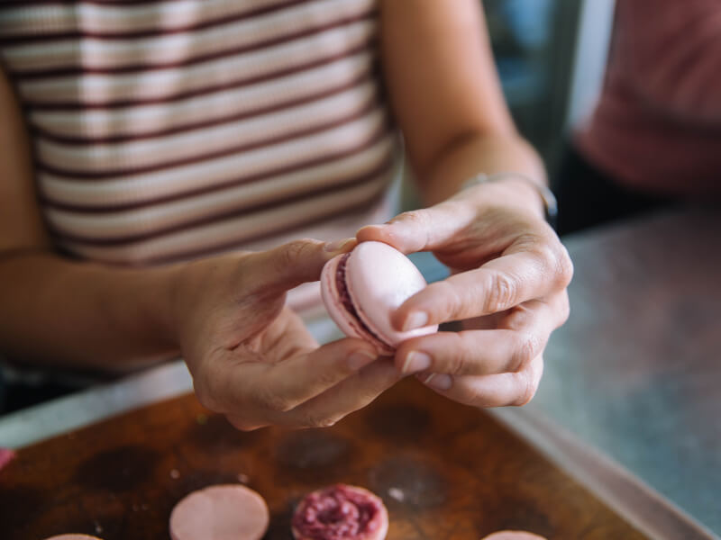 A person is holding a pink macaron