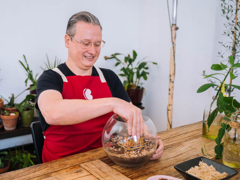 A man sits at a table adding plants to a terrarium on Father's Day in London