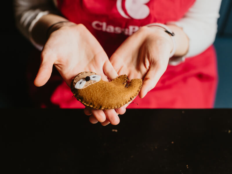 A close up of two hands holding a handmade felt sloth toy