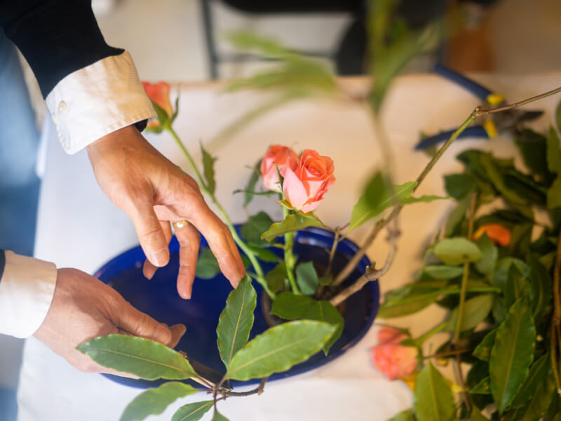 A close up of a person holding a rose stem at a Japanese flower arranging class