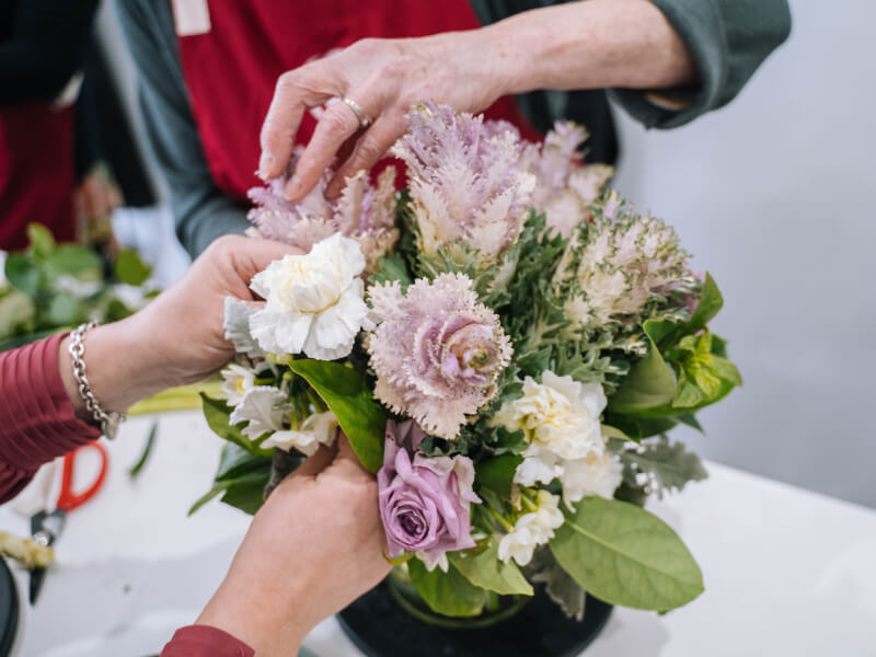 A close up of two people arranging a bouquet of flowers