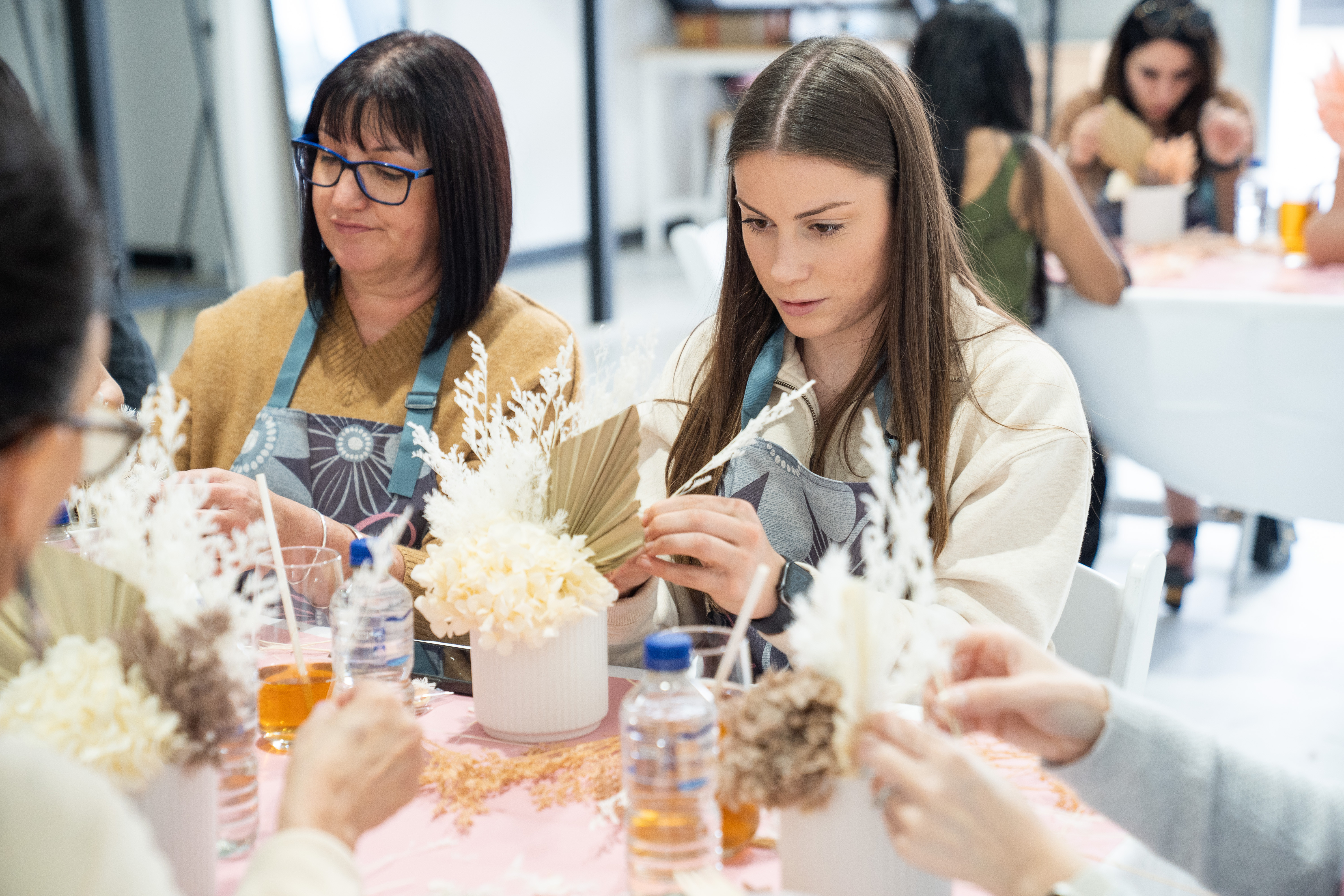 Two women are at a floristry workshop for Mother's Day, making dried flower arrangements