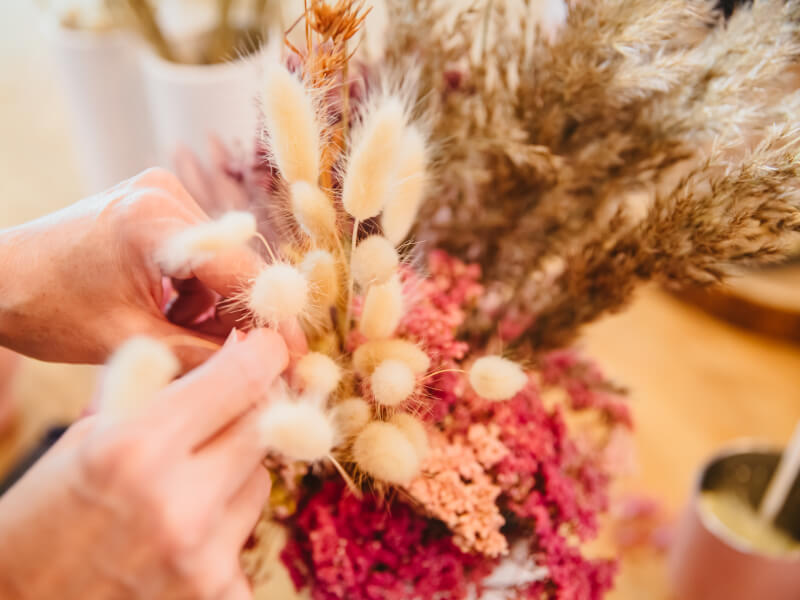 Hands working with dried flowers in a floristry class