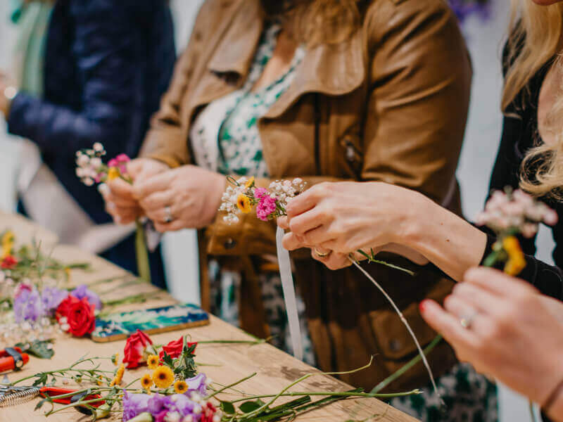 A close up of several people making flower crowns