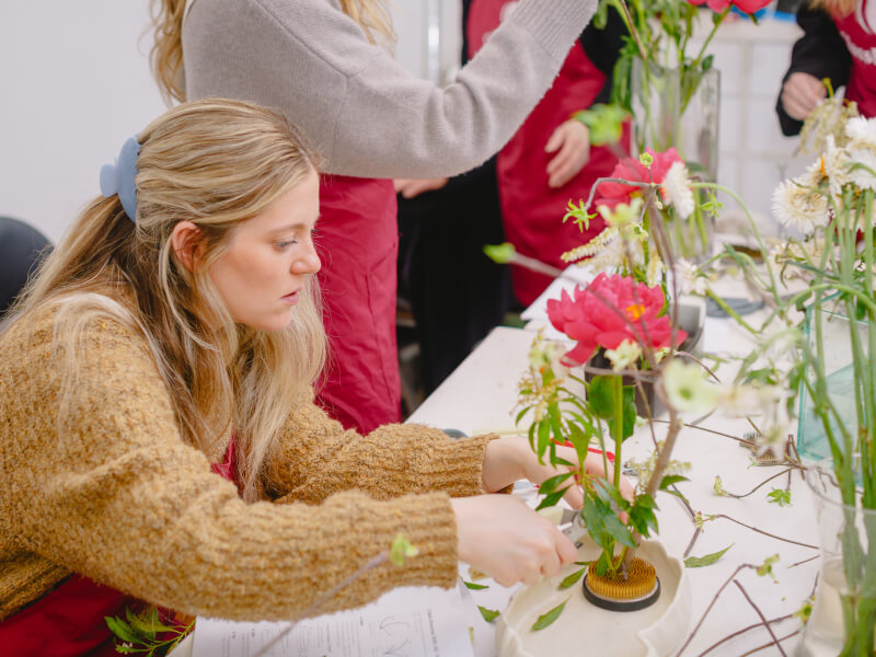 Woman clipping plants in a flower arranging class