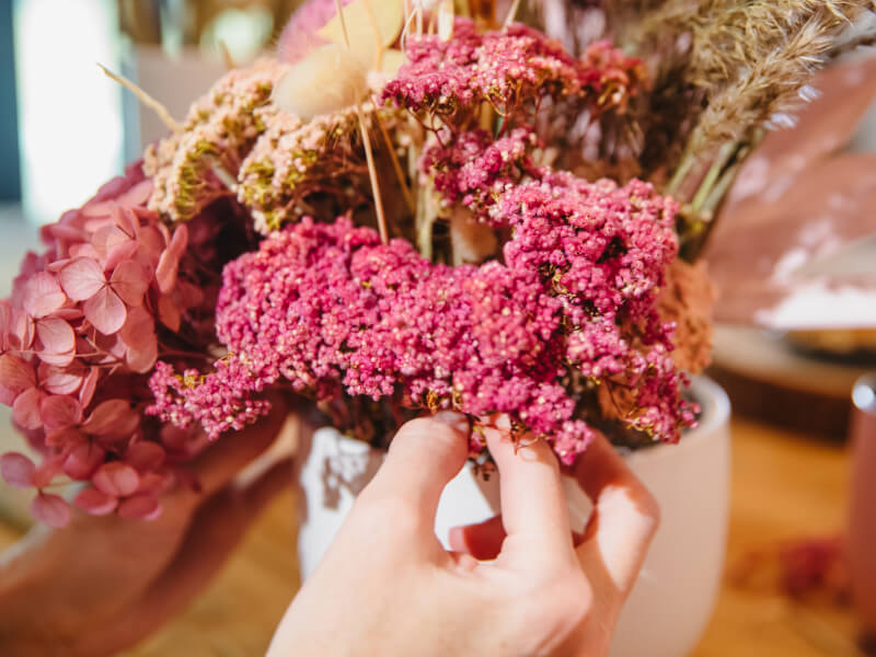 A close up of a person at a floristry class in Manchester arranging a hand tied bouquet of pink flowers