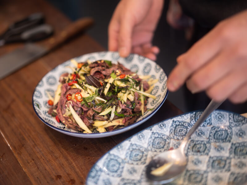 A close up of a small blue patterned bowl filled with vegetables and meat