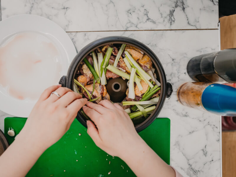 A top down shot of a person arranging meat and vegetables in a bowl