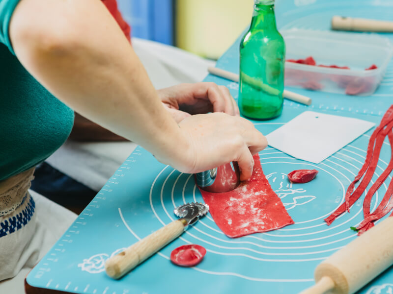 A close up shot of a person cutting out circles from fresh red pasta dough