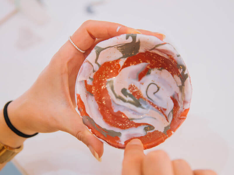 A hand holding polymer clay with several coloured blended together