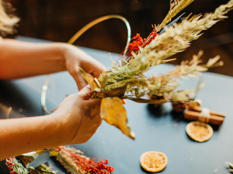 A close up of a person making a dried flower wreath 