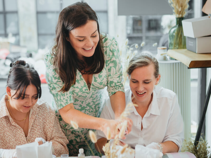 A teacher is instructing two women at a perfume making class