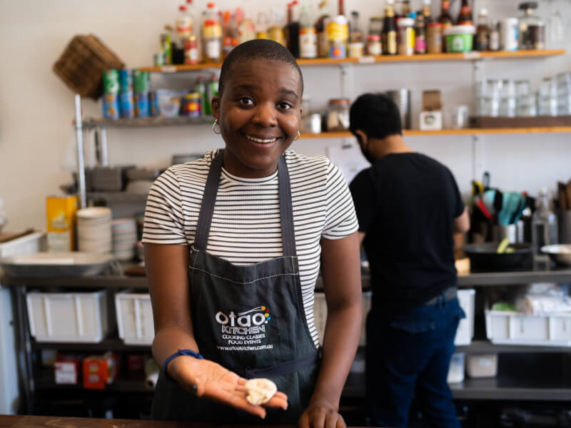 A woman is holding a handmade dumpling and smiling