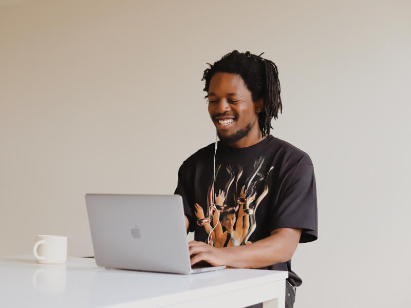A smiling man looks at his laptop at friends before his online cooking class.