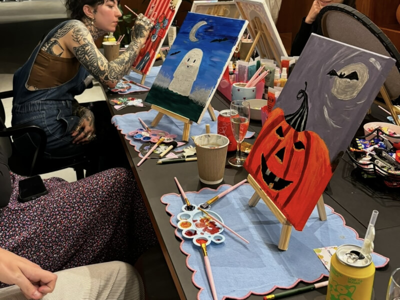 A woman painting a picture at a Halloween themed paint and sip class