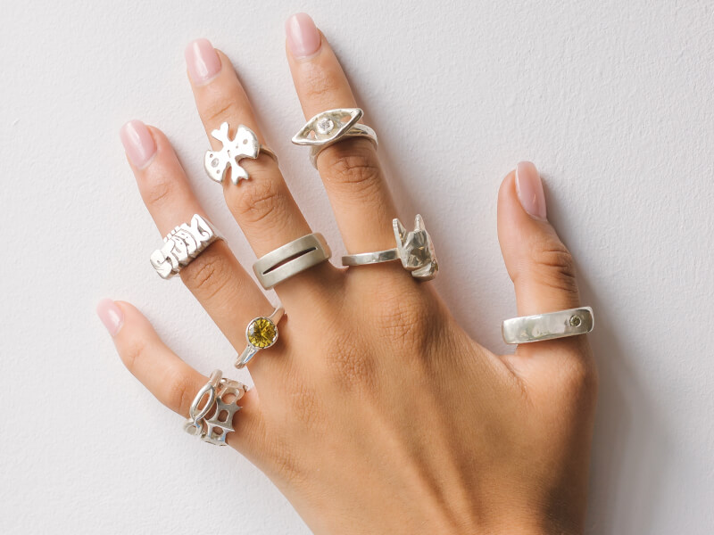 A hand wearing lots of silver handmade rings