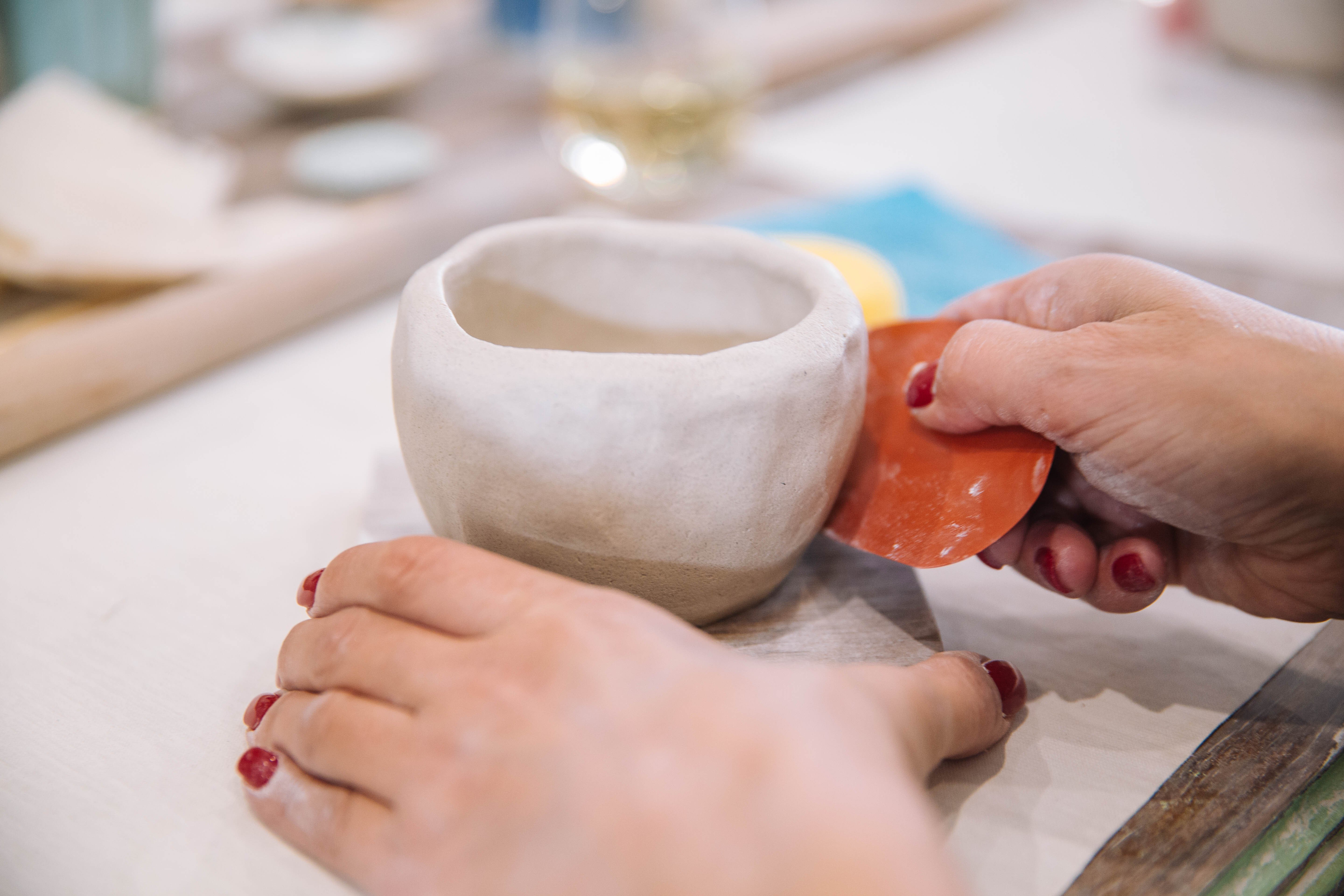Person using a small tool to shape a clay vessel