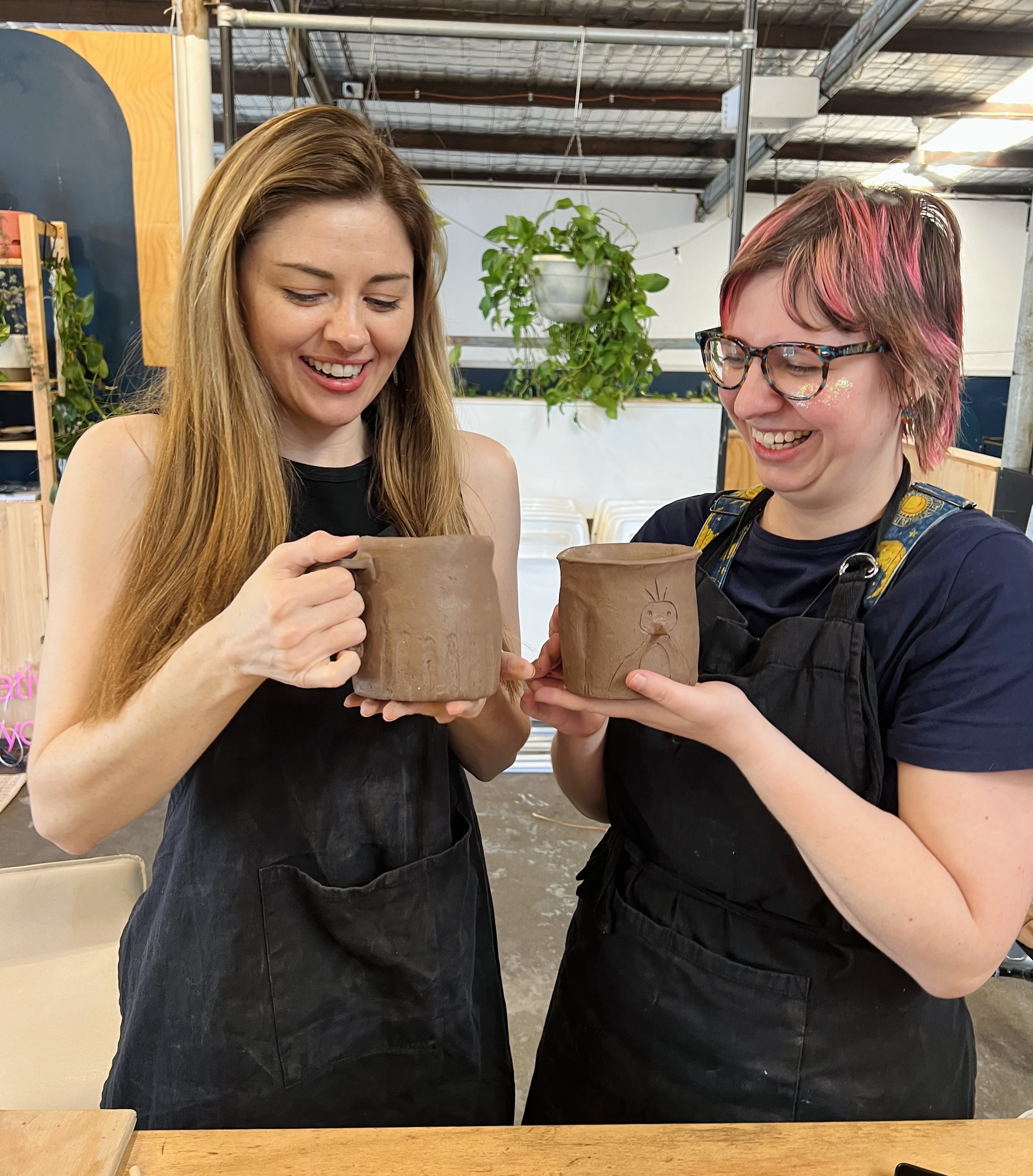 Two women holding their pottery at a handbuilding class