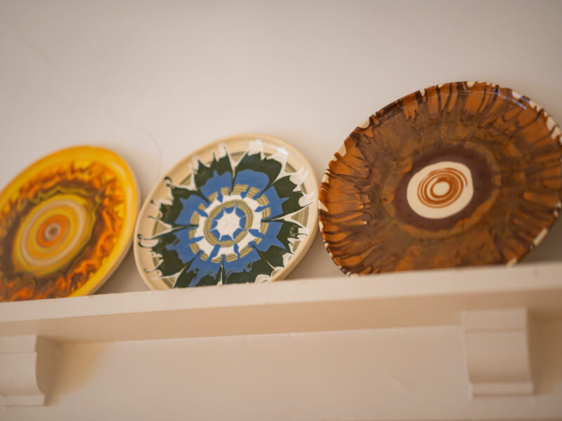 A selection of three hand painted plates sit on top of a shelf
