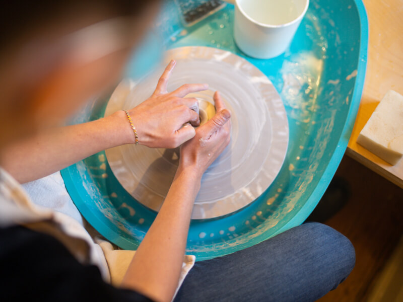 Hands working clay on a pottery wheel