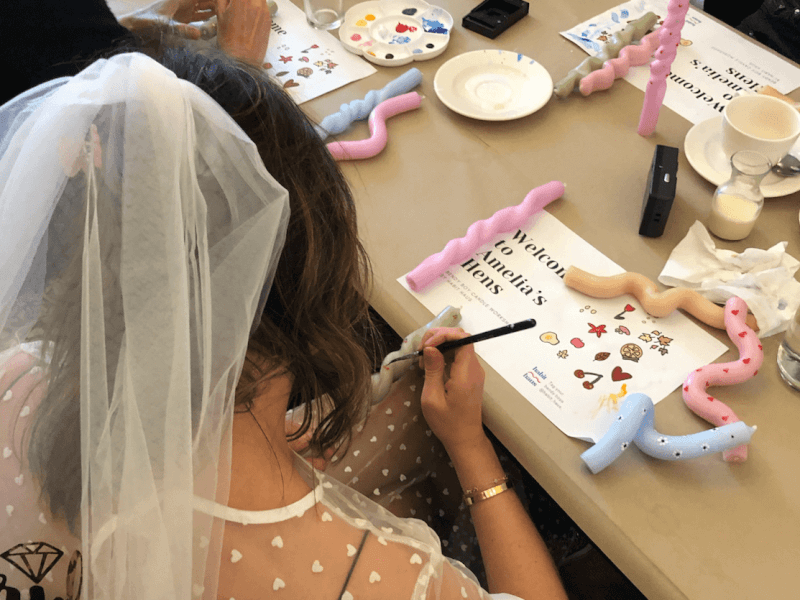 A bride-to-be at a Bendy Boy candle making class is painting a green twisted candle