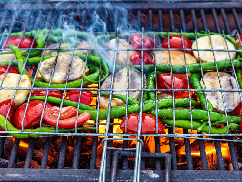 Fresh green veg and tomatoes on a bbq griddle in the sunshine