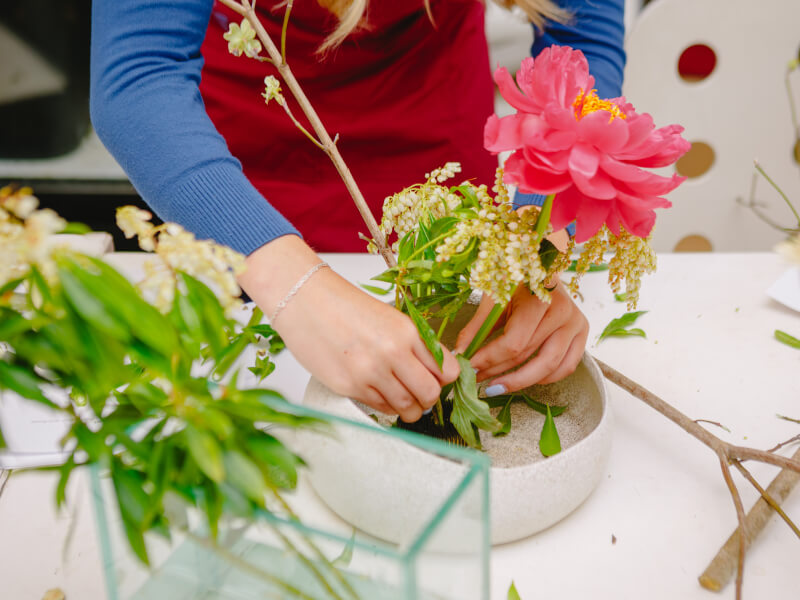 A close up of a person making an ikebana arrangement