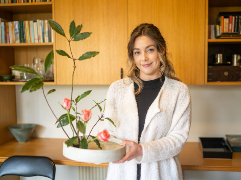 A woman is holding a finished ikebana piece