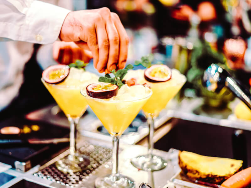 man garnishing a cocktail with passionfruit