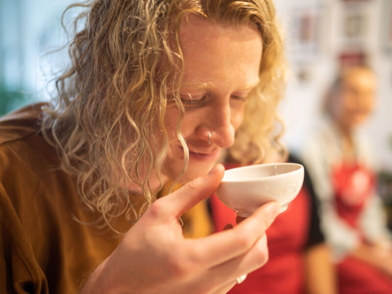 A man is smelling a small bowl of spice at an Indian cooking workshop
